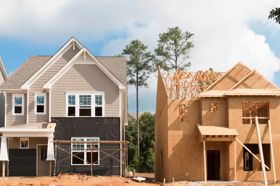 Two wood-frame houses under construction.